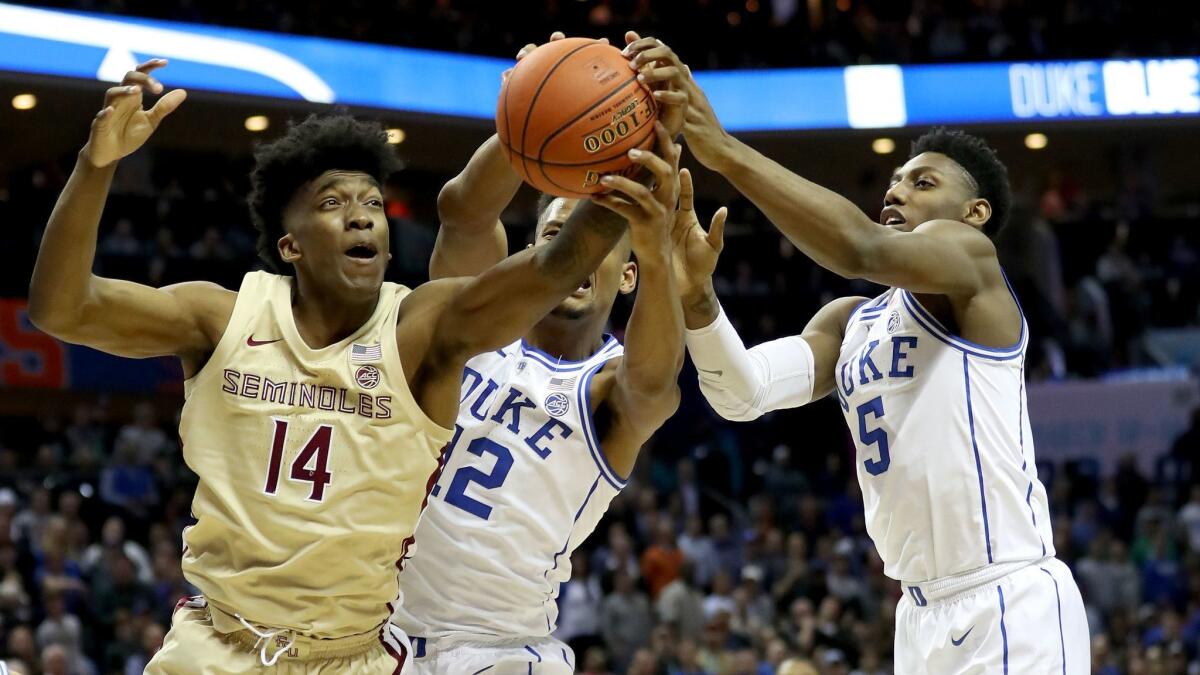 Duke teammates Javin DeLaurier (12) and RJ Barrett (5) battle for possession against Florida State's Terance Mann (14) during the ACC championship game on Saturday in Charlotte, N.C.