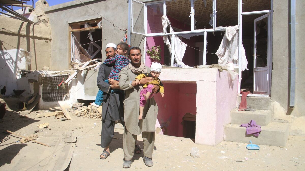 Afghans hold their injured children at a house near the scene of a suicide bomb blast in Ghazni, Afghanistan, on Sunday.