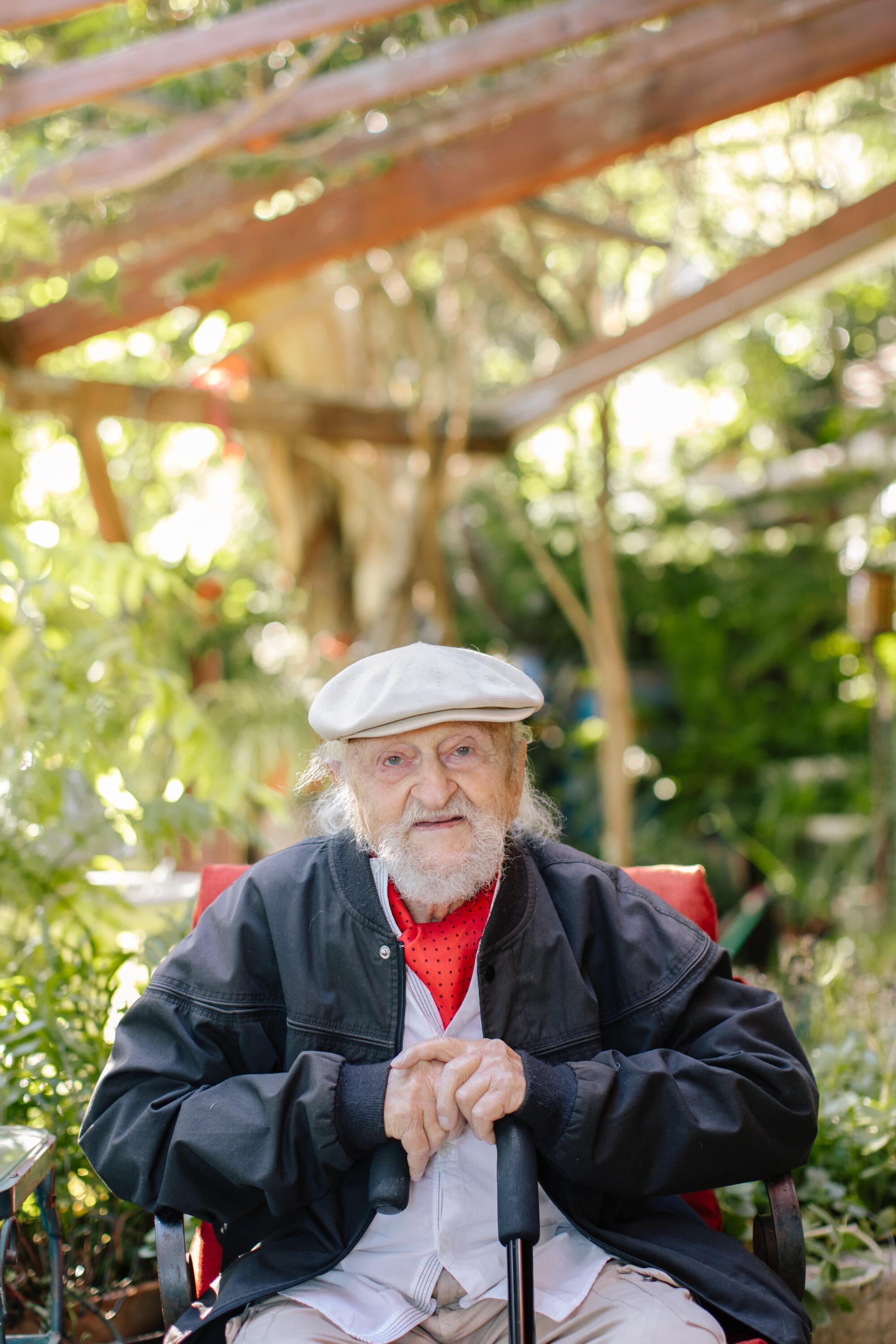 A bearded older man seated in a chair. 