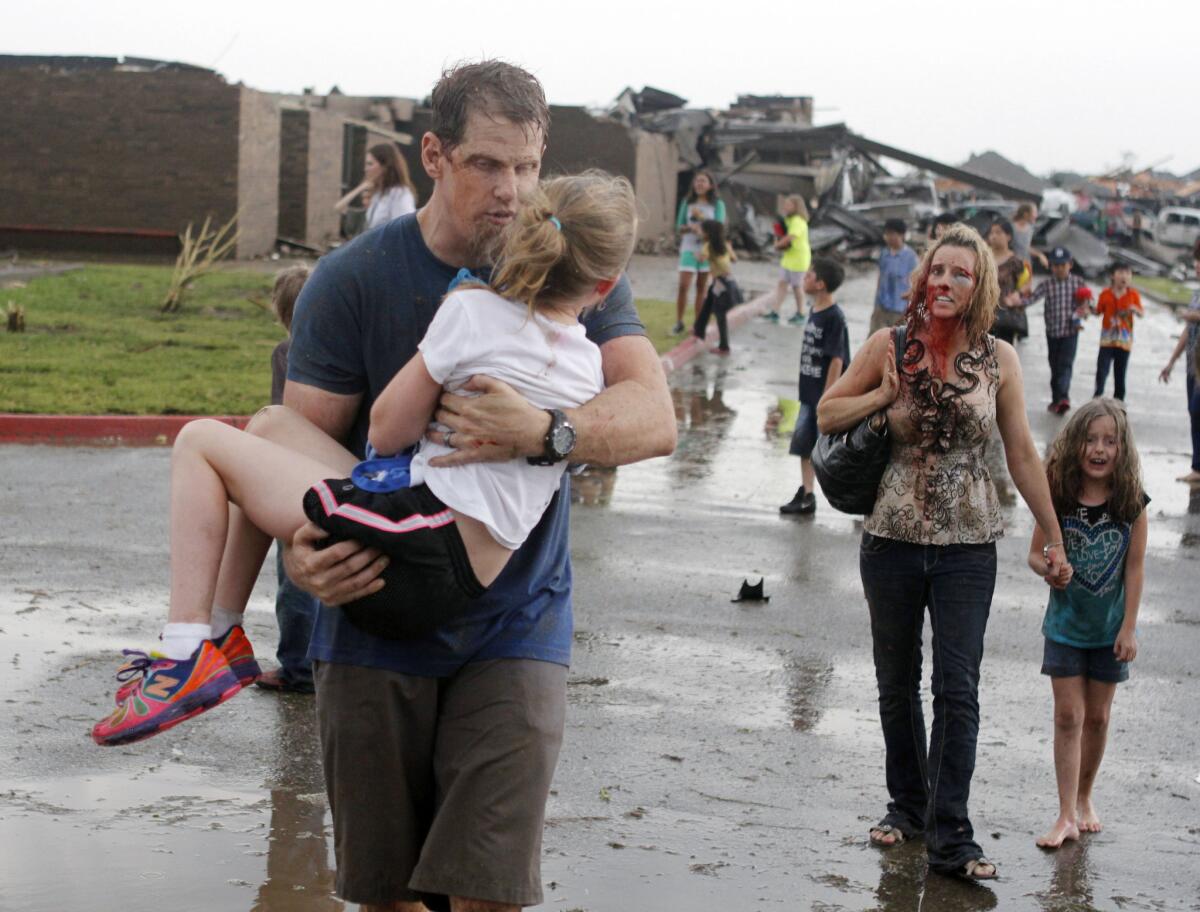 Teachers carry children away from Briarwood Elementary after a tornado destroyed the school in south Oklahoma City on May 20, 2013. Officials are now debating how to pay for putting storm shelters in public schools.