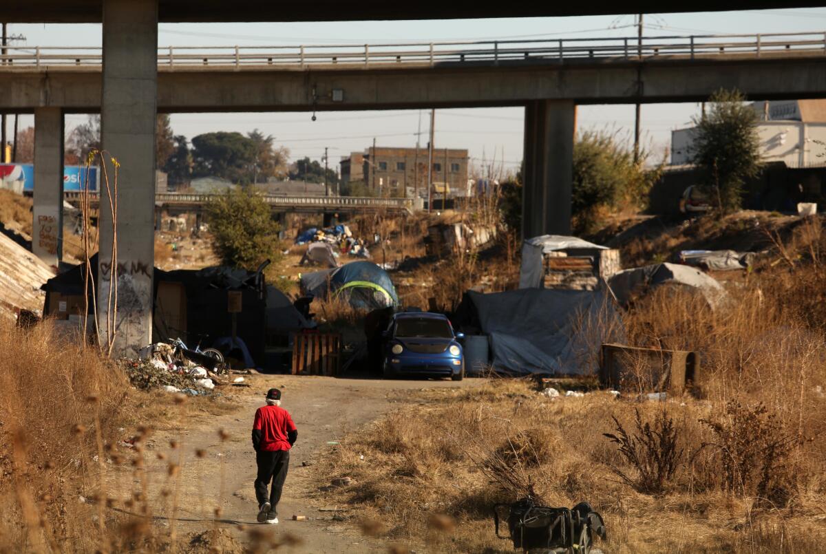 A man makes his way to a homeless encampment under an overpass