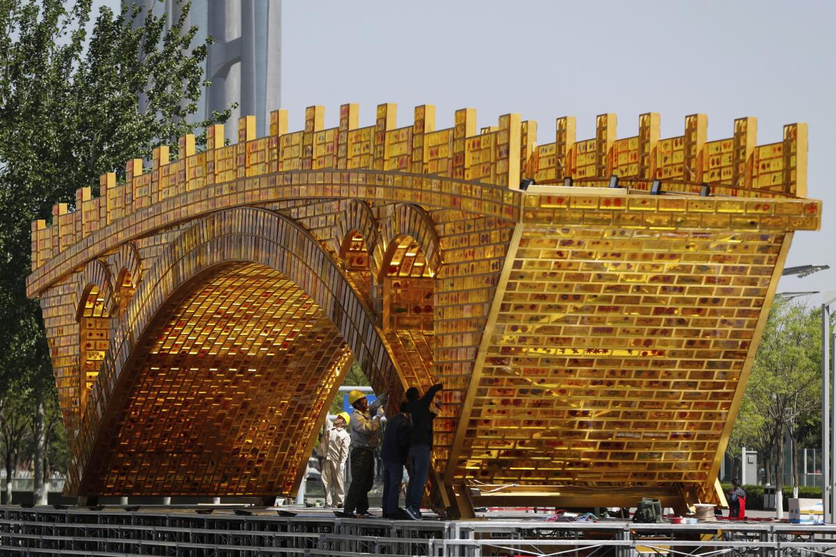 Workers last month install wires on the "Golden Bridge of Silk Road" structure outside the National Convention Center in Beijing. (Andy Wong / Associated Press) (Andy Wong / AP)