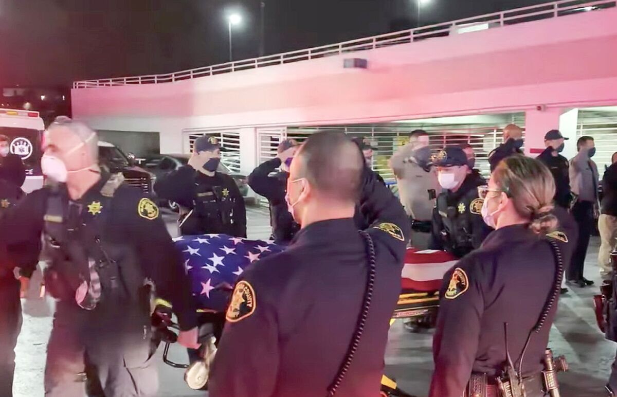 Law enforcement personnel salute a flag-draped body