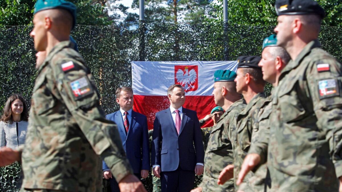 Polish soldiers parade before Polish President Andrzej Duda, center right, and Defense Minister Mariusz Baszczak, center left, during their visit to the Adazi military base in Latvia on June 28, 2018.