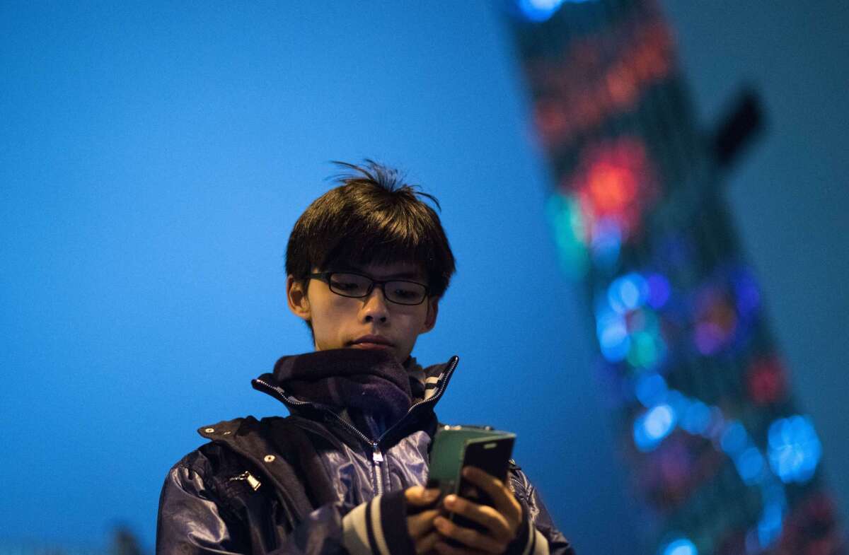 Joshua Wong looks at his cellphone after addressing protesters in the Admiralty district of Hong Kong in December 2014.