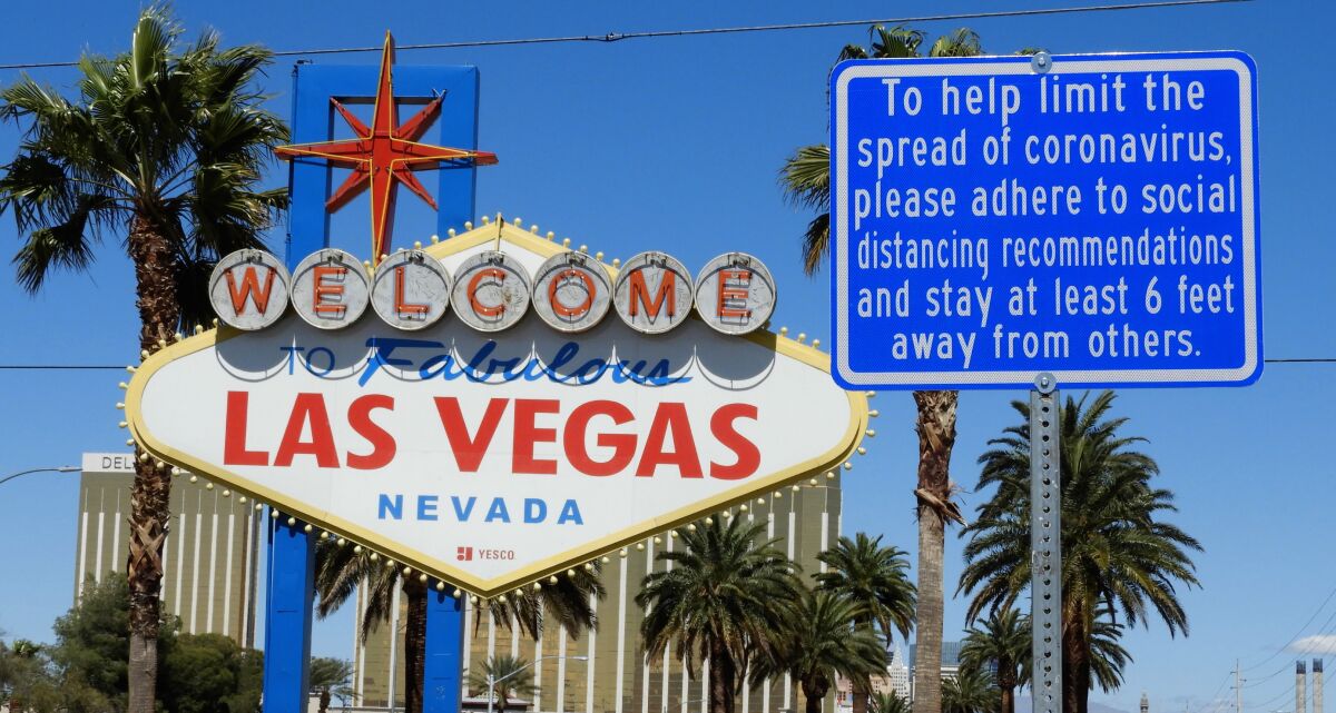 A large, white sign that reads "Welcome to fabulous Las Vegas Nevada," next to a blue sign with COVID-19 guidelines