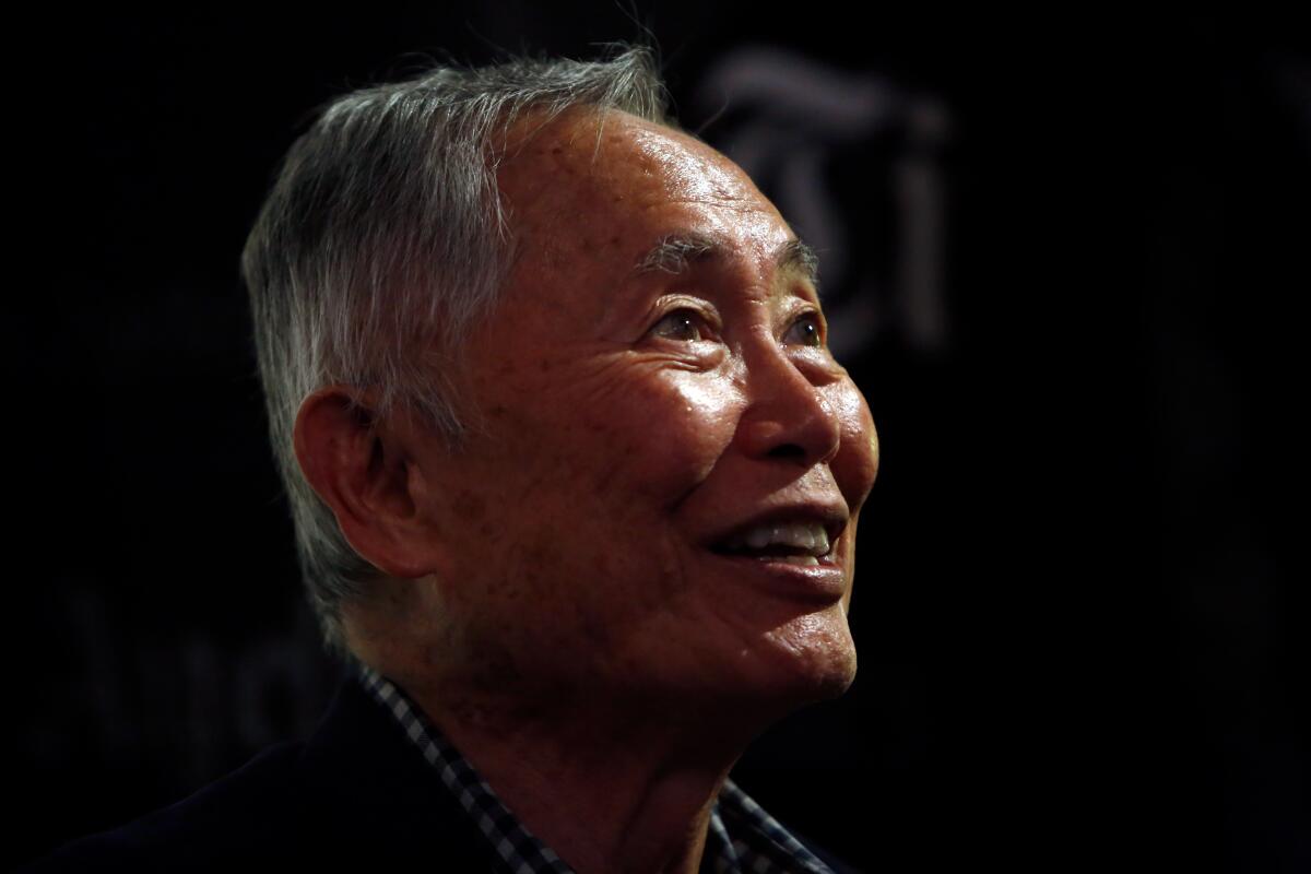 Man with gray hair smiling and looking upward to the right in darkened room