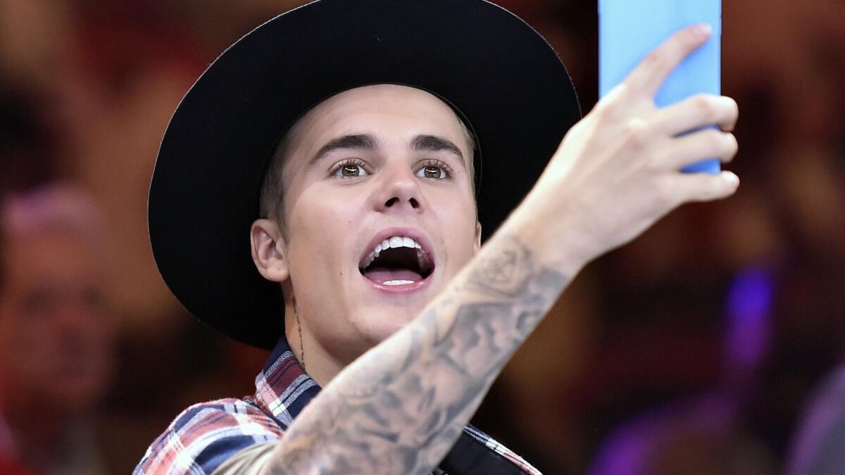 Singer Justin Bieber wields his cellphone camera at a June fight in Las Vegas.