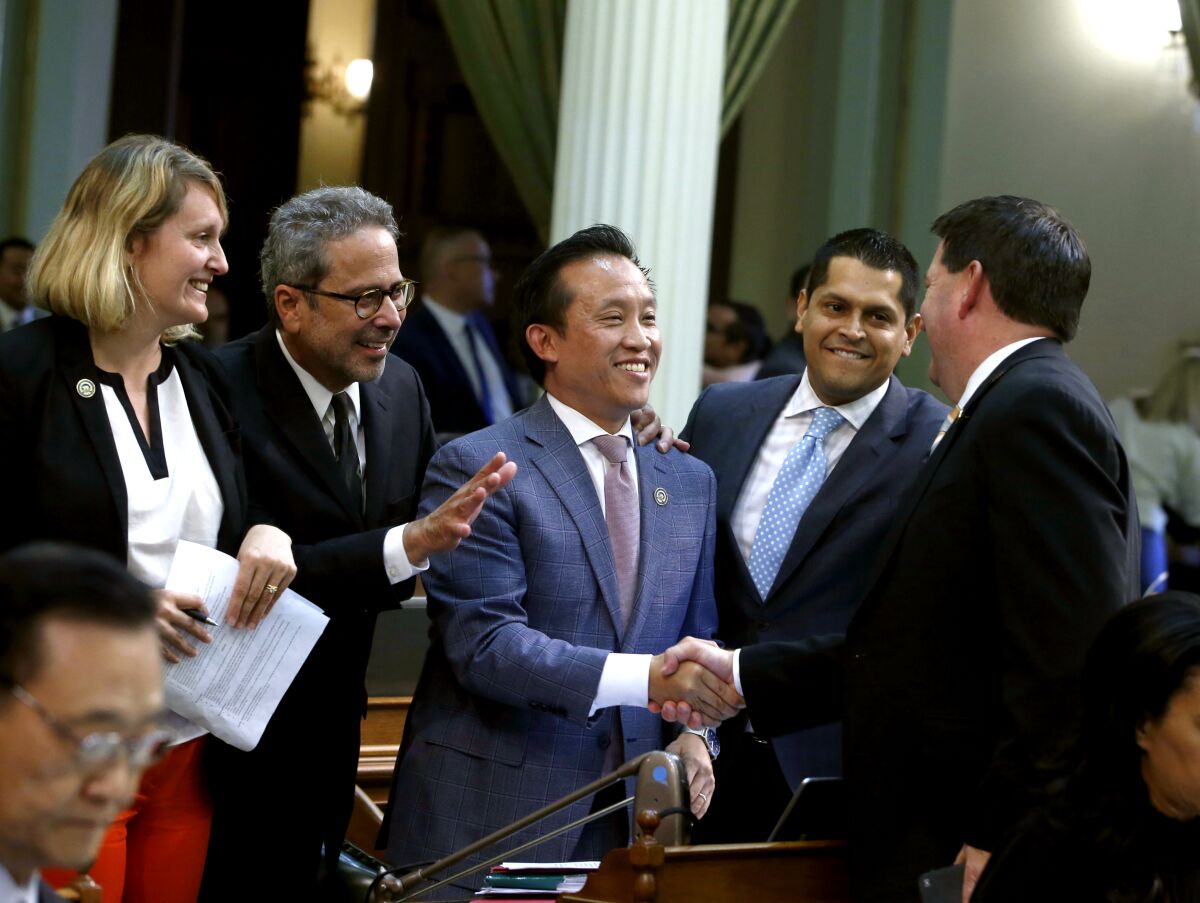 Assemblyman David Chiu, center, is congratulated after his rent-cap bill passed the Legislature