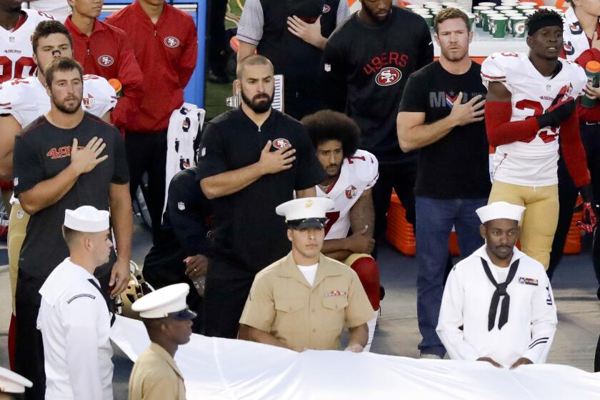 San Francisco 49ers quarterback Colin Kaepernick, center, refuses to stand during the national anthem before the team's NFL preseason football game against the San Diego Chargers on Thursday in San Diego.