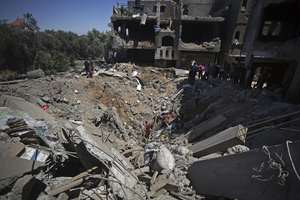 Palestinians inspect the damage of a destroyed house that was hit by an Israeli airstrike in town of Khan Younis, southern Gaza Strip, Wednesday, May 19, 2021. (AP Photo/Yousef Masoud)