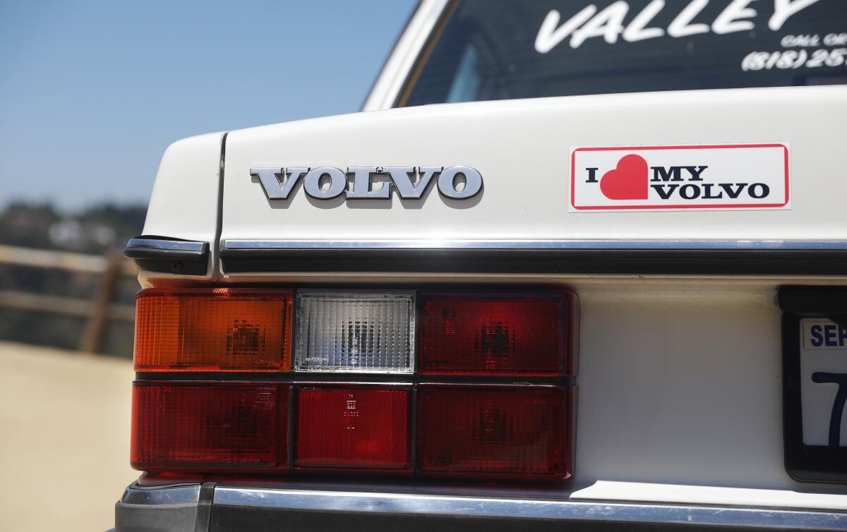 A boxy white Volvo with an 'I [heart] my Volvo' sticker on the back