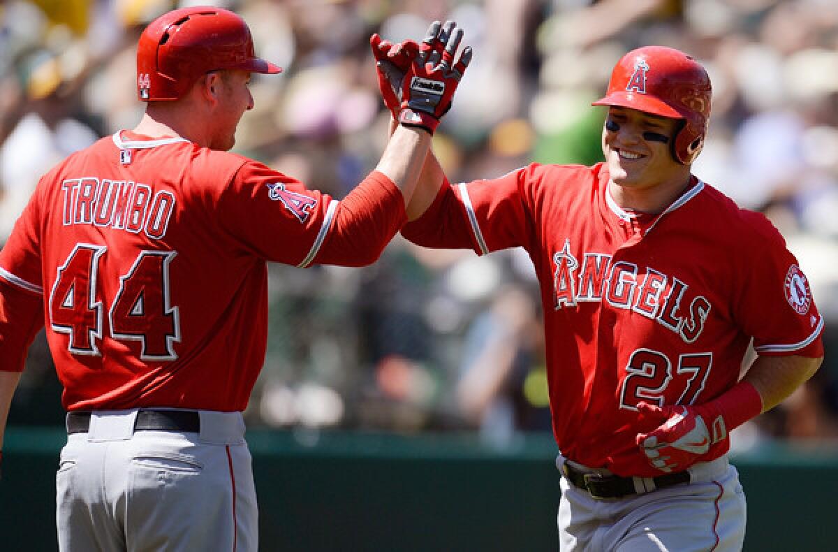 Angels left fielder Mike Trout is congratulated by designated hitter Mark Trumbo after hitting a home run against the A's in the sixth inning Wednesday afternoon in Oakland.