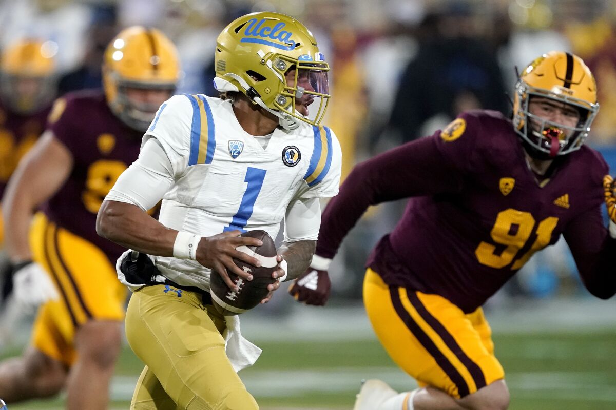 UCLA quarterback Dorian Thompson-Robinson scrambles as Arizona State defensive end Michael Matus pursues.