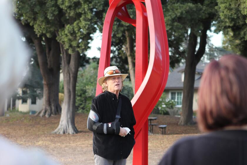 Artist Bret Price stands next to his piece titled Godot, which is one of eight installations at the Muckenthaler Cultural Center sculpture garden, at their Fullerton landmark location on Thursday, Nov. 12, 2020.