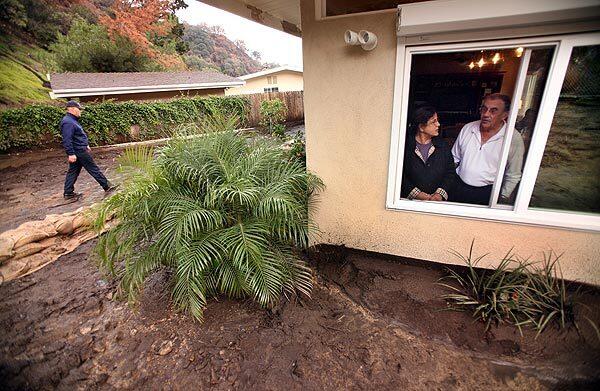 Gary and Diane Stibal survey the mud and debris flow that filled their backyard on Normanton Drive in La Canada Flintridge after an unexpected downpour Thursday night. Six homes were damaged. The Stibals had spent $35,000 on precautionary measures because their backyard faces a hillside denuded by the Station fire.