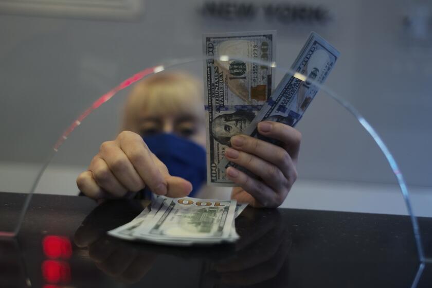 FILE - A woman counts U.S. dollar banknotes inside a currency exchange shop, in Ankara, Turkey, Monday, March 22, 2021. As the value of the U.S. dollar soars, other currencies around the world are sinking by comparison. (AP Photo/Burhan Ozbilici, File)