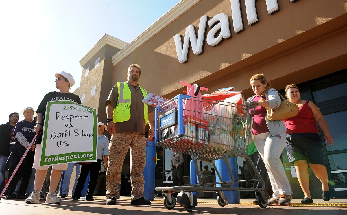 Shoppers walk past protesters outside a Wal-Mart store in Paramount on Nov. 23, 2012.