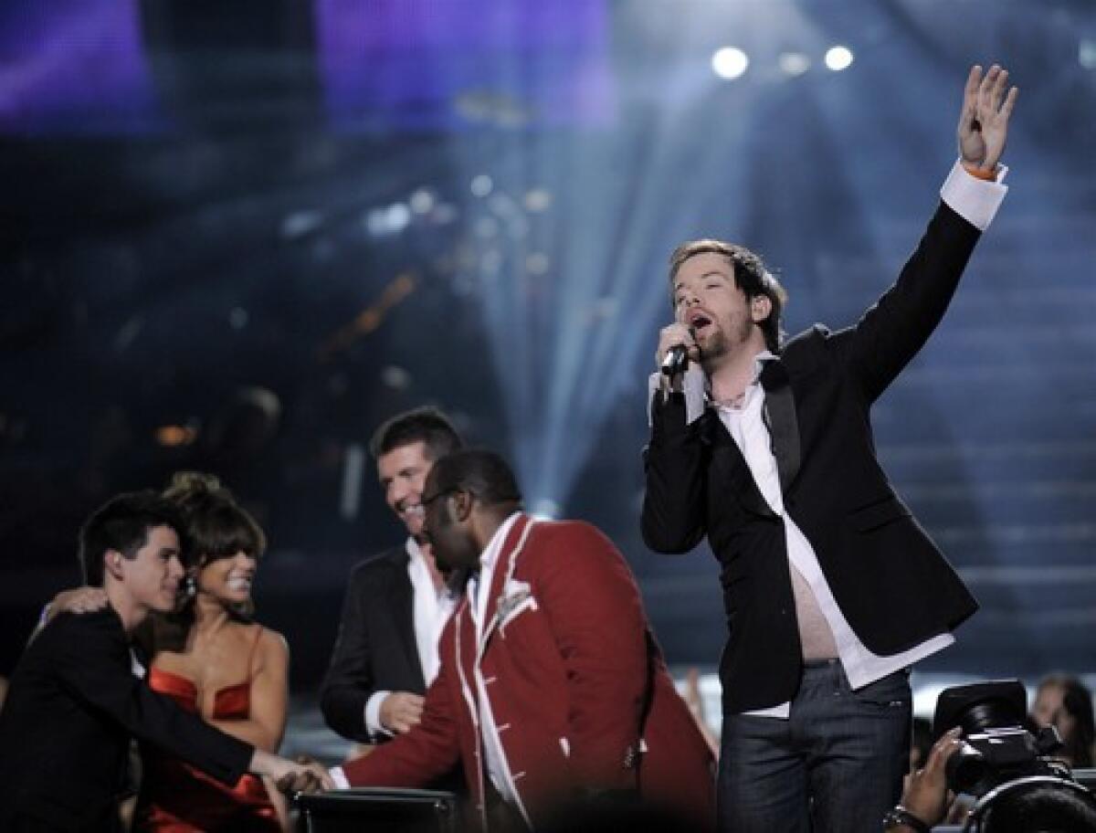 David Cook perfoms after winning on the 7th season of "American Idol." In the background, runner-up David Archuleta shakes hands with the judges.
