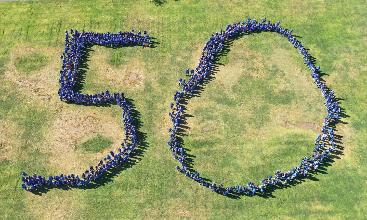 An aerial photograph of the current Westwood Elementary students who formed the number 50 on a school field.