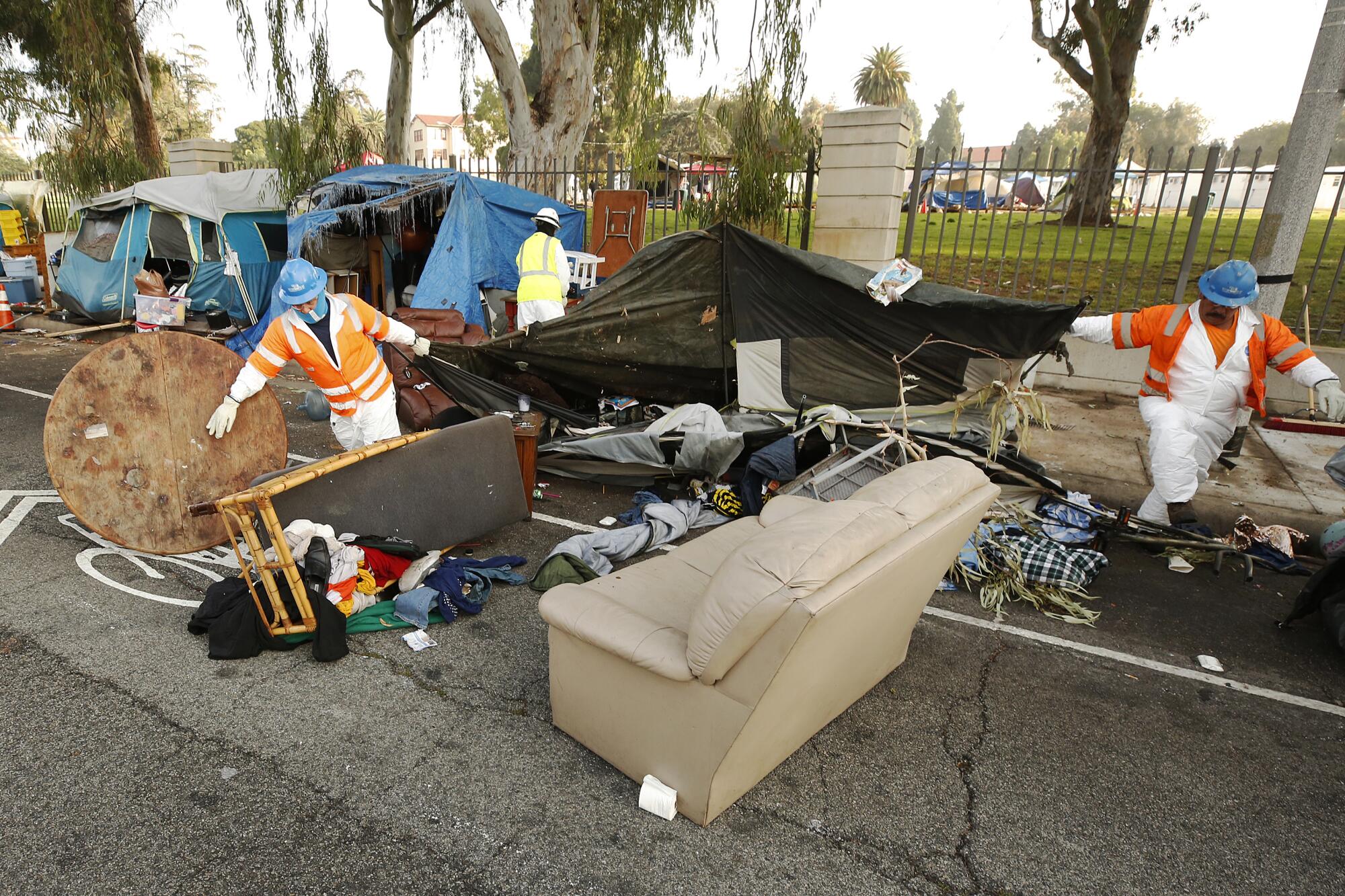 Members of the clean-up crew dismantle tents located on the Veterans Row homeless encampment.