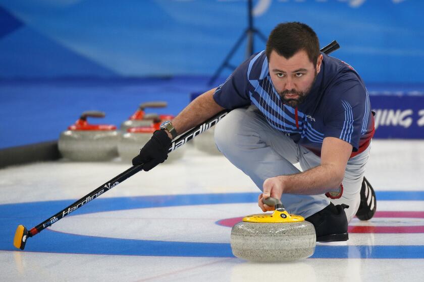 An intense John Landsteiner from the U.S. Olympic Curling team prepares to release the curling stone.