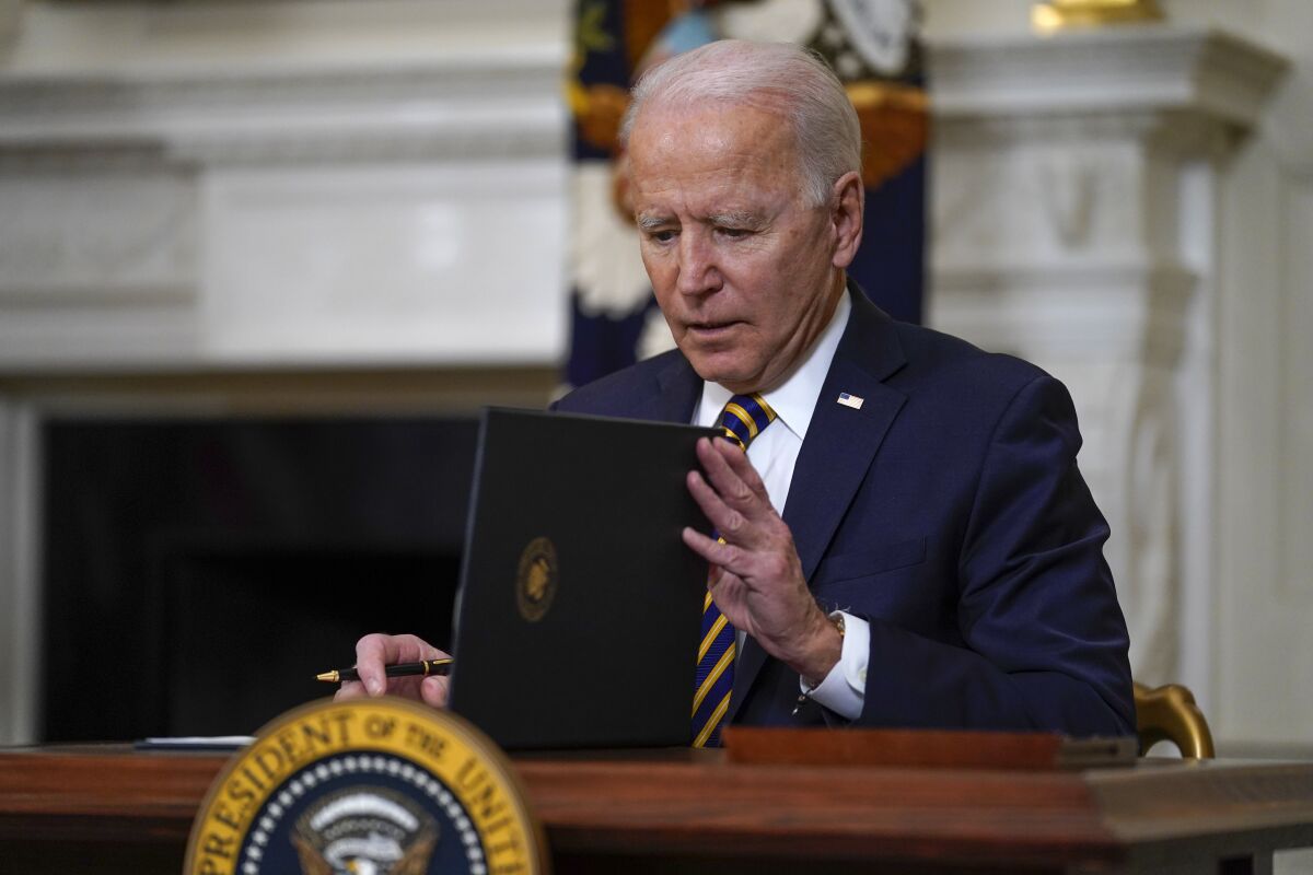 President Biden closes a folder after signing an executive order 