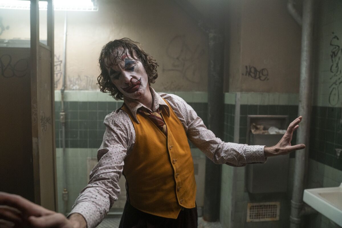 Joaquin Phoenix as the "Joker" in a public restroom with graffiti on the walls.