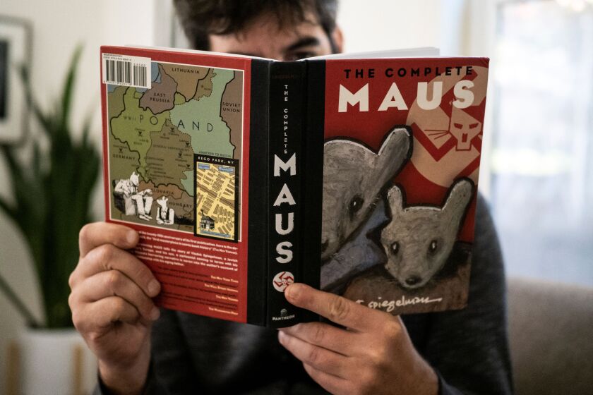 This illustration photo taken in Los Angeles, California on January 27, 2022 shows a person holding the graphic novel "Maus" by Art Spiegelman. - A school board in Tennessee has added to a surge in book bans by conservatives with an order to remove the award-winning 1986 graphic novel on the Holocaust, "Maus," from local student libraries. Author Art Spiegelman told CNN on January 27 -- coincidentally International Holocaust Remembrance Day -- that the ban of his book for crude language was "myopic" and represents a "bigger and stupider" problem than any with his specific work. - RESTRICTED TO EDITORIAL USE - MANDATORY MENTION OF THE ARTIST UPON PUBLICATION - TO ILLUSTRATE THE EVENT AS SPECIFIED IN THE CAPTION (Photo by Maro SIRANOSIAN / AFP) / RESTRICTED TO EDITORIAL USE - MANDATORY MENTION OF THE ARTIST UPON PUBLICATION - TO ILLUSTRATE THE EVENT AS SPECIFIED IN THE CAPTION / RESTRICTED TO EDITORIAL USE - MANDATORY MENTION OF THE ARTIST UPON PUBLICATION - TO ILLUSTRATE THE EVENT AS SPECIFIED IN THE CAPTION (Photo by MARO SIRANOSIAN/AFP via Getty Images)