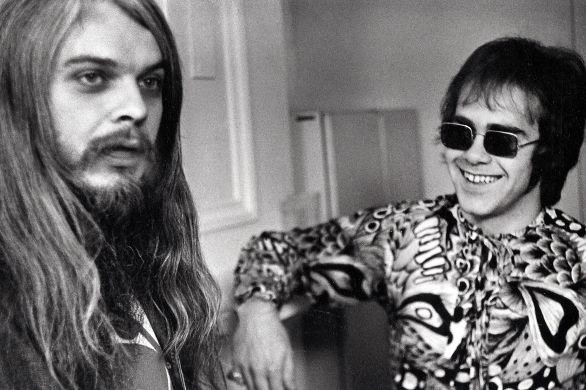 Leon Russell and Elton John smile as they interact.