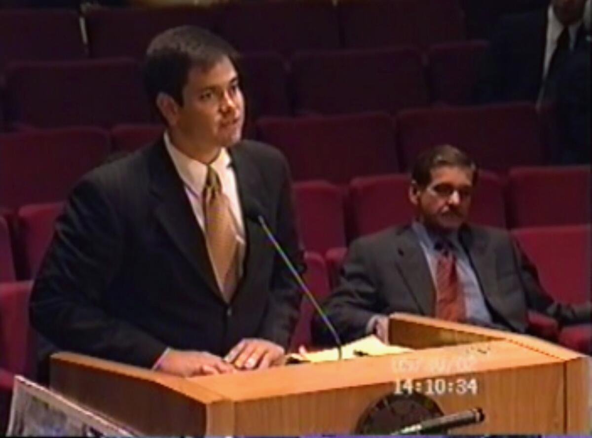 Marco Rubio, a la izquierda, en una reunión del condado Miami-Dade, expresando su apoyo a un proyecto de construcción promovido por Carlos C. Lopez-Cantera, sentado a la derecha. Foto tomada del video de la reunión el 30 de mayo del 2002. (Miami-Dade Board of County Commissioners via AP)