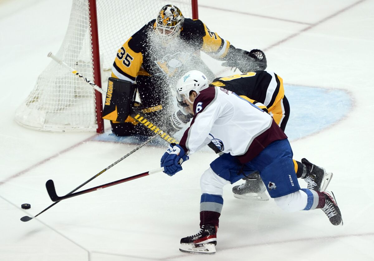 Pittsburgh Penguins' Brian Dumoulin, center, knocks the puck away as Colorado Avalanche's Erik Johnson (6) shoots on goaltender Tristan Jarry (35) during the third period of an NHL hockey game, Tuesday, April 5, 2022, in Pittsburgh. The Avalanche won 6-4. (AP Photo/Keith Srakocic)