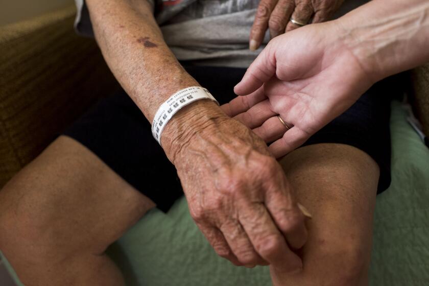 DOVER-FOXCROFT, ME - JULY 25: Beth Lagasse, 55, checks the band of her father James Lagasse, 84, after his first night at a nursing home on July 25, 2019 in Dover-Foxcroft, Maine. James had a stroke the previous week and spend days in the hospital. "It's been a freakin' battle not knowing what direction to go in, not knowing what to do next," Beth said of her father's quick transition to the nursing home. (Photo by Marlena Sloss/The Washington Post via Getty Images)