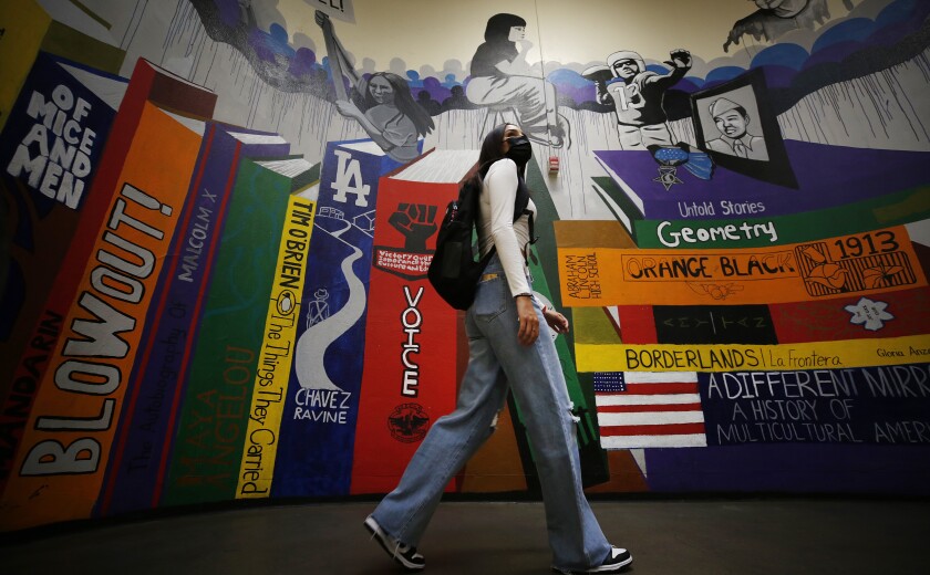 A teenage girl walks by a colorful mural.