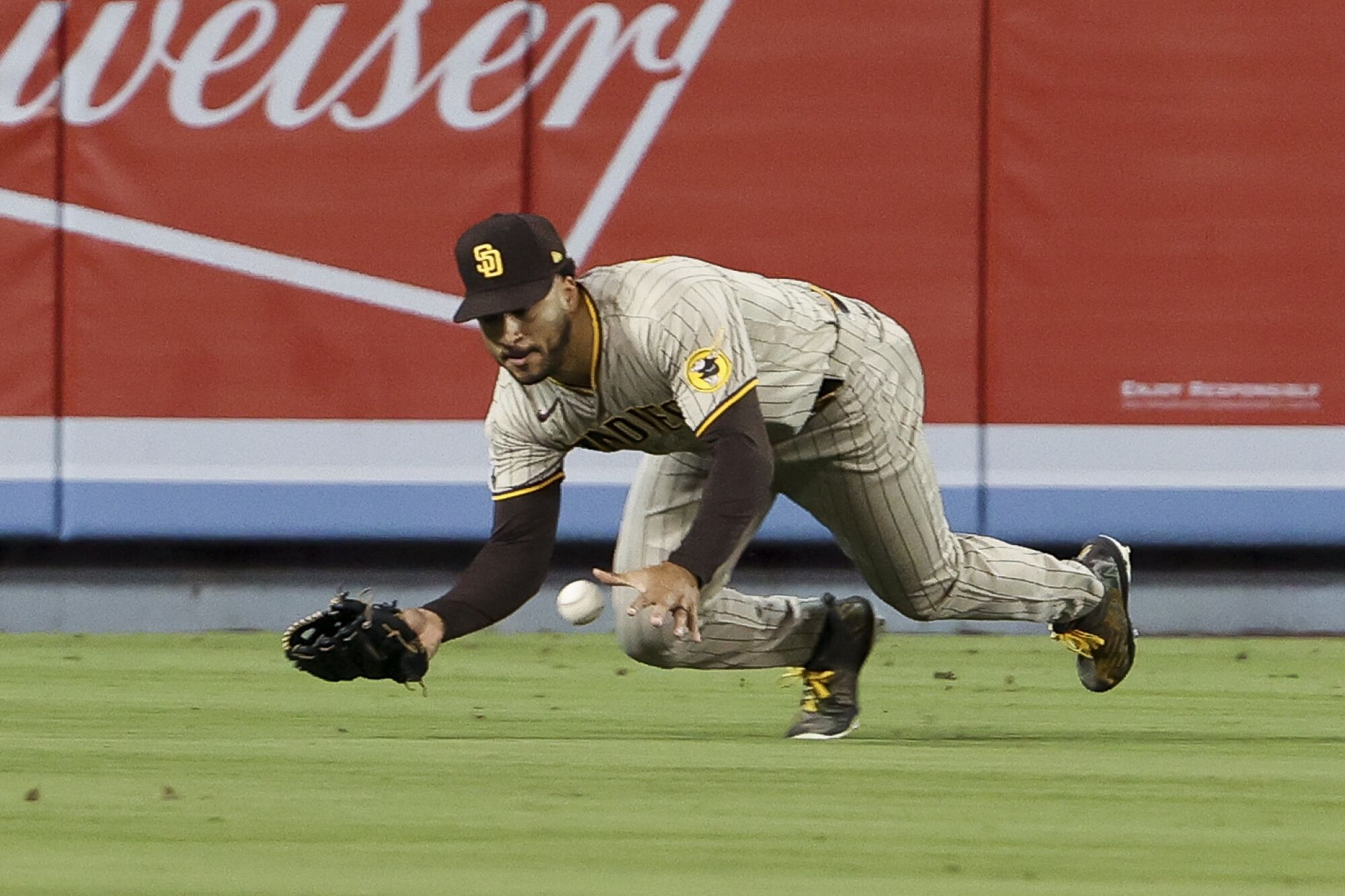  Padres center fielder Trent Grisham dives for ball hit by Dodgers' Mookie Betts during the seventh inning.