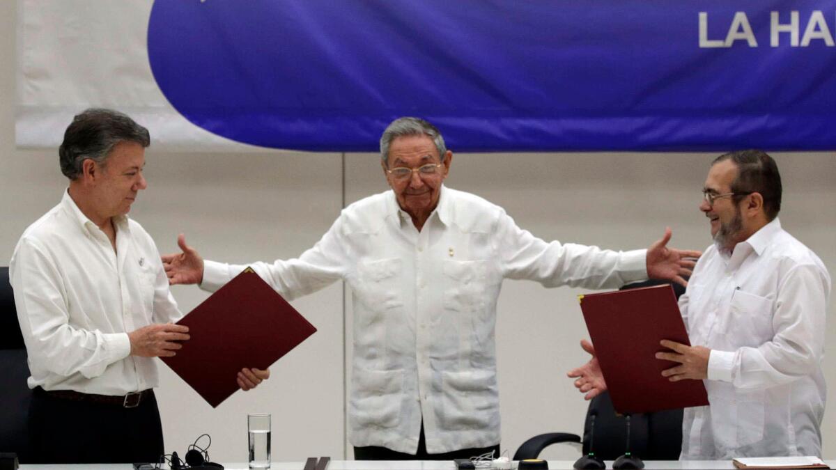 Cuban President Raul Castro, center, motions to Colombian President Juan Manuel Santos, left, and Commander of the Revolutionary Armed Forces of Colombia, Rodrigo Londono, in June during a signing ceremony for a ceasefire.