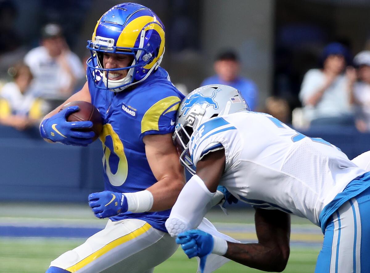 Rams receiver holds the ball tightly as he is tackled