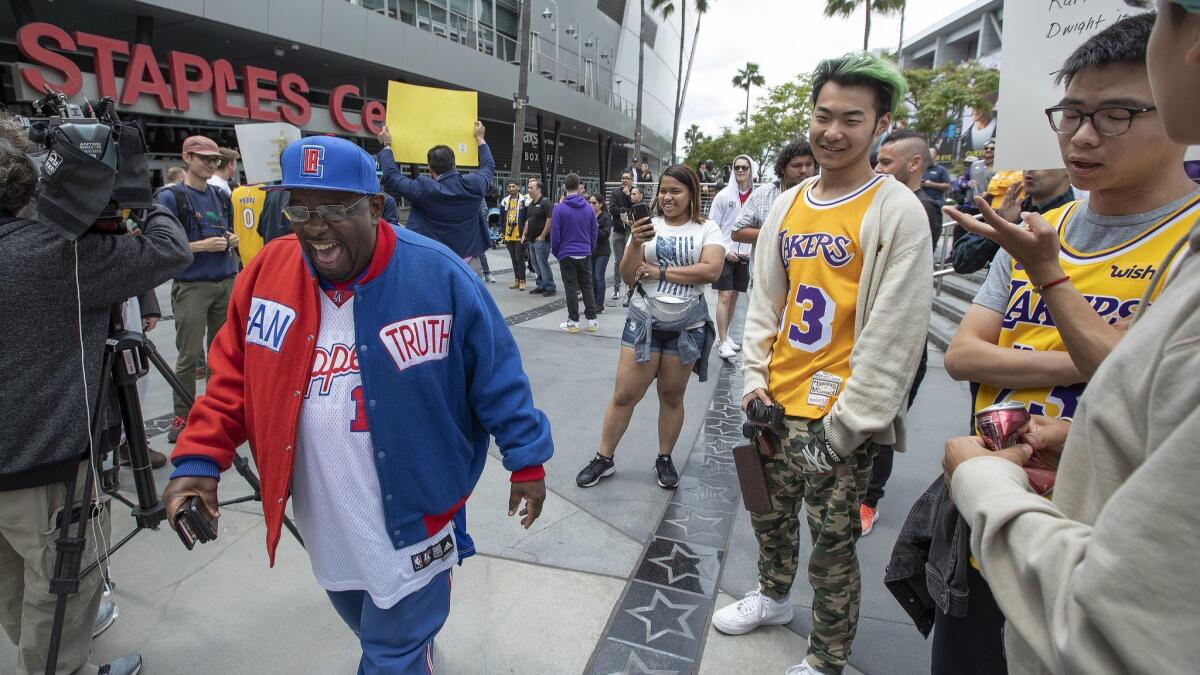 Clippers fan Darrell Bailey, left, better known as Clipper Darrell, laughs while walking through a group of protesting Lakers fans outside Staples Center on May 10.