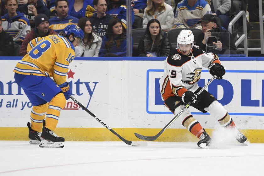 Anaheim Ducks' Troy Terry (19) and St. Louis Blues' Robert Thomas (18) fight for the puck during the third period of an NHL hockey game Monday, Nov. 21, 2022, in St. Louis. (AP Photo/Michael Thomas)