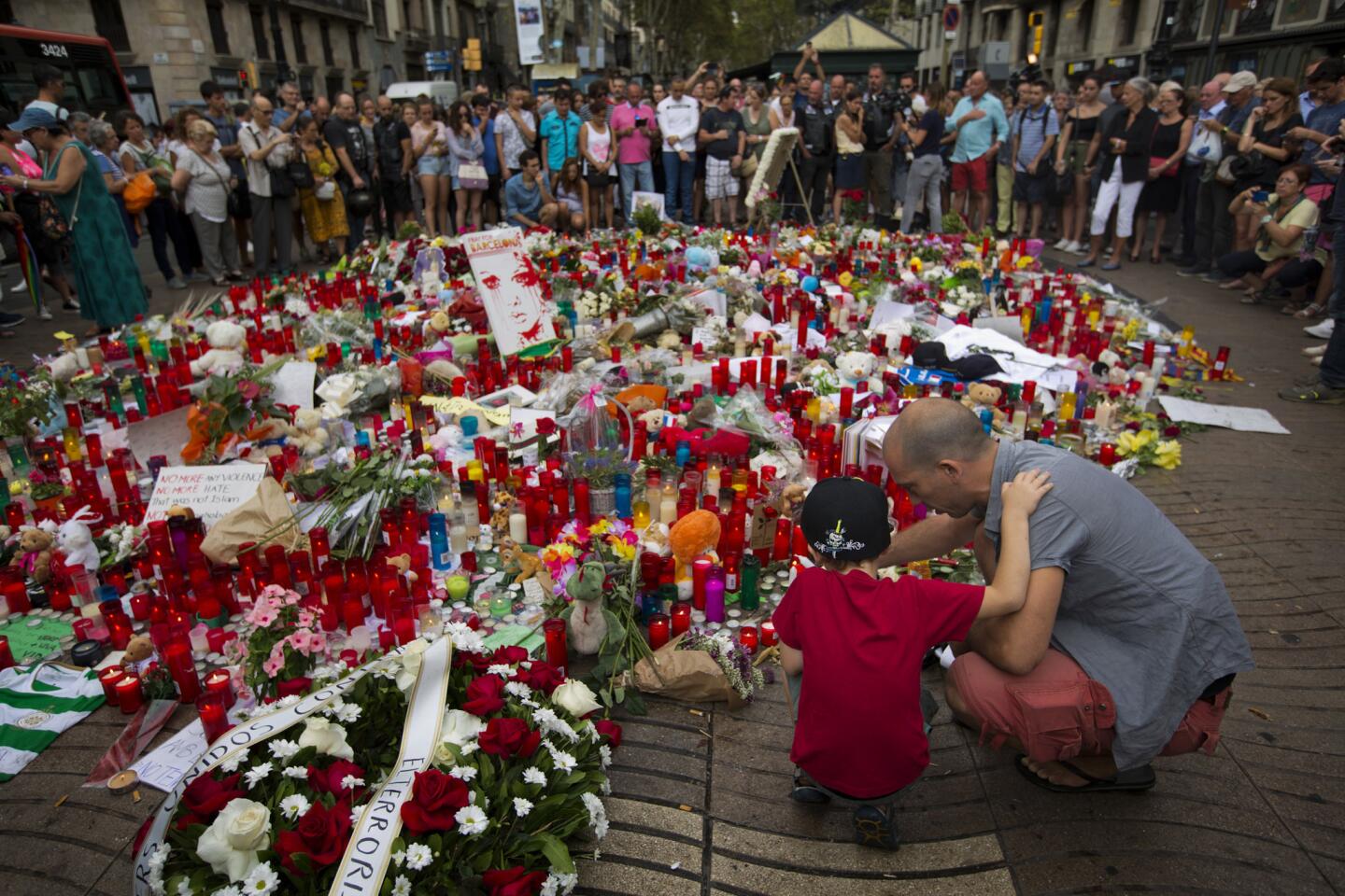 A man with his son light candles at a memorial to victims of a terror attack on Barcelona's Las Ramblas promenade in Barcelona, Spain on Aug. 19, 2017.
