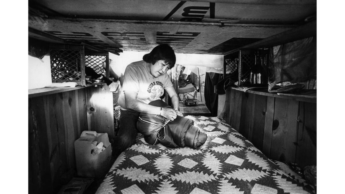 Feb. 5, 1984: Wilma Aros ties up bedrolls after making up bed inside makeshift shelter on Bunker Hill.