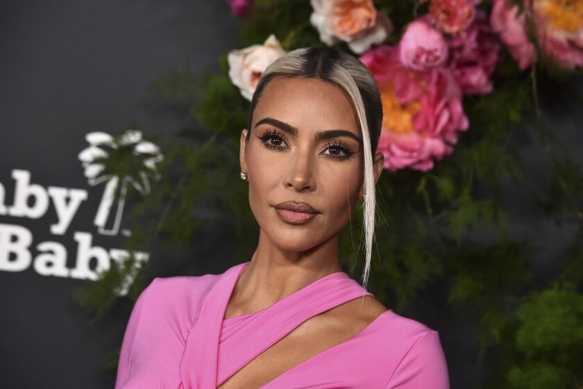 woman, kim kardashian, torso and face, standing on red carpet in pink outfit with hair up, with platinum blonde highlights