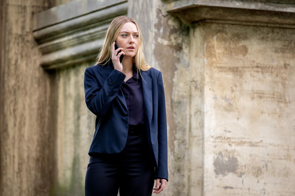 A woman in a blue blazer speaks on a cell phone.