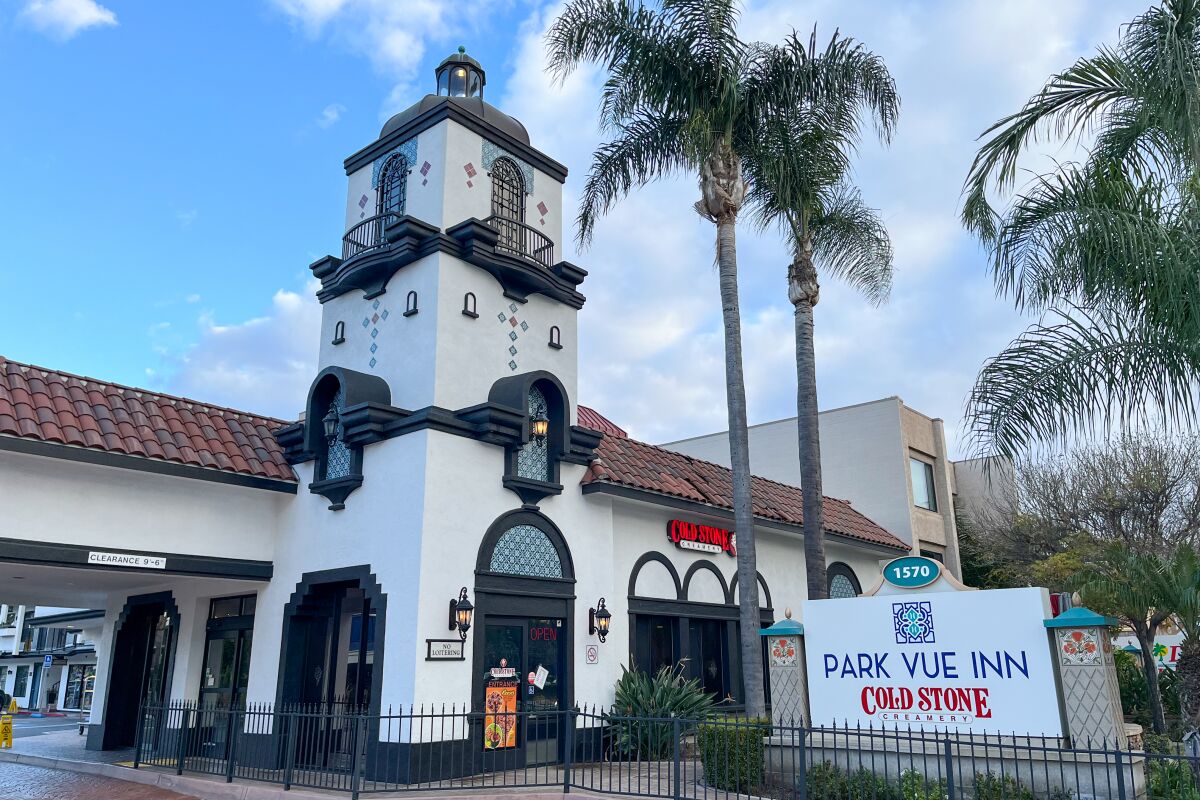 The white Spanish-style exterior of a hotel with fence in front and a sign that says Park Vue Inn
