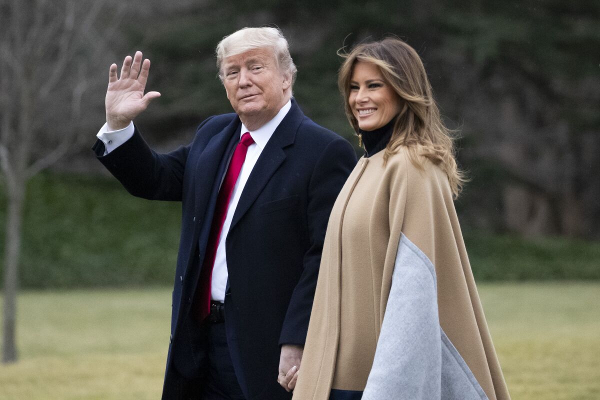 President Donald Trump, accompanied by first lady Melania Trump, waves as he walks on the South Lawn.