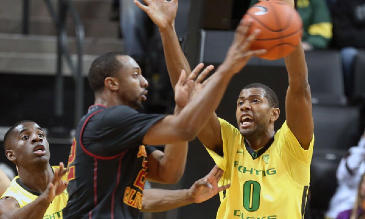 USC's Byron Wesley, center, passes the ball under pressure from Oregon's Damyean Dotson, left, and Mike Moser during the Trojans' 78-66 loss Saturday.