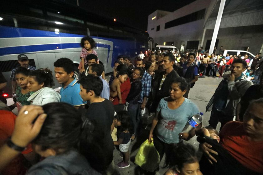 NUEVO LAREDO, MEXICO, CA - AUGUST 2, 2019 - - Honduran asylum seekers line up to board one of four Chiapas-bound buses in a parking lot at an immigration check-point in Nuevo Laredo, Mexico on August 2, 2019. When the buses finally arrived in Nuevo Laredo at about 1 a.m. Friday, nearly 200 migrants rushed to line up. Many were smiling, relieved. One woman exclaimed: ÒThank God we can go!Ó Migrants were released into cartel-weary Nuevo Laredo this week stayed and slept in the parking lot of the immigration check-point for days struggling to find food, water and other necessities. Many headed back to their home country. (Genaro Molina / Los Angeles Times)