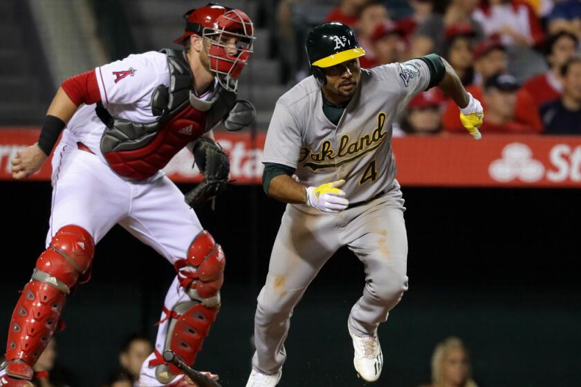 Oakland Athletics' Coco Crisp, right, singles as Angels catcher Jett Bandy looks on during the sixth inning on Saturday at Angel Stadium.