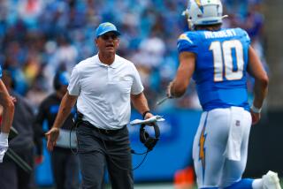 Chargers coach Jim Harbaugh meets Justin Herbert as he runs off the field against  the Carolina Panthers.