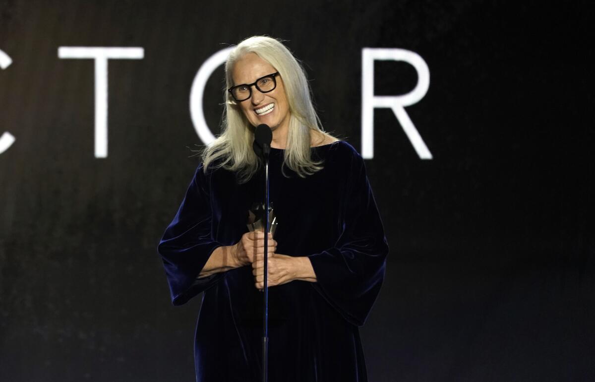 Jane Campion holding a trophy and smiling into a microphone